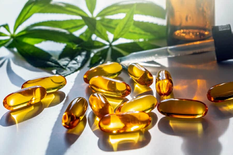 Golden cannabis oil softgel capsules with a cannabis leaf and dropper